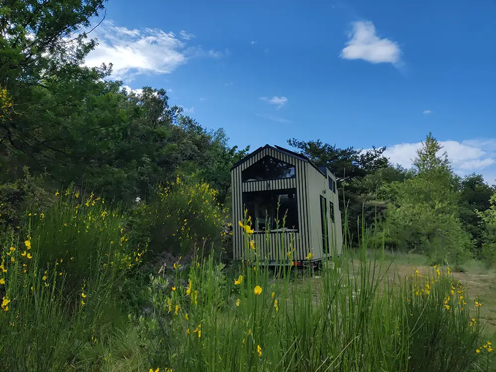 Aménagement intérieur d'une tiny house. Tiny house au milieu de la nature et des genêts.