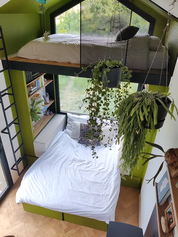 Aménagement intérieur d'une tiny house. Canapé convertible en lit double vue de haut depuis la grande mezzanine.