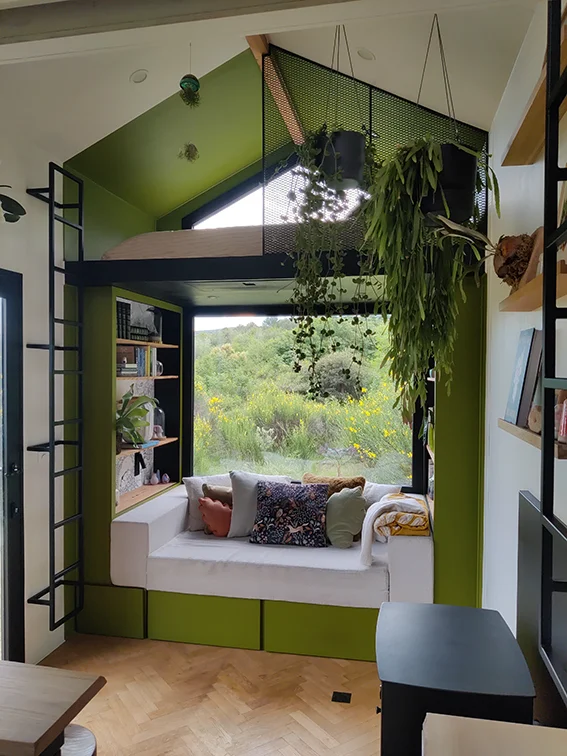 Aménagement intérieur d'une tiny house. Niche verte qui épouse les formes structurelles de la tiny house.