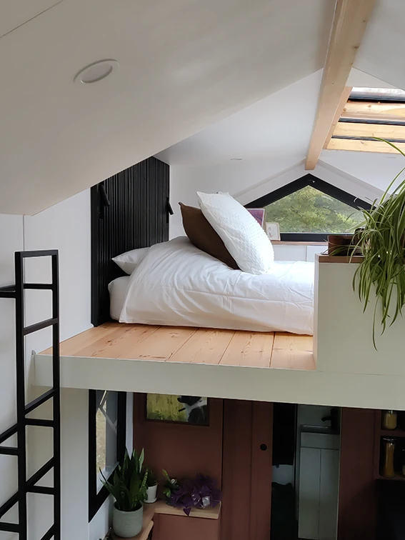 Aménagement intérieur d'une tiny house. Espace chambre double et ses coussins textures.