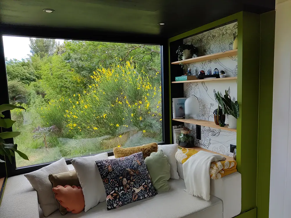 Aménagement intérieur d'une tiny house. Coin canapé et coussins divers.