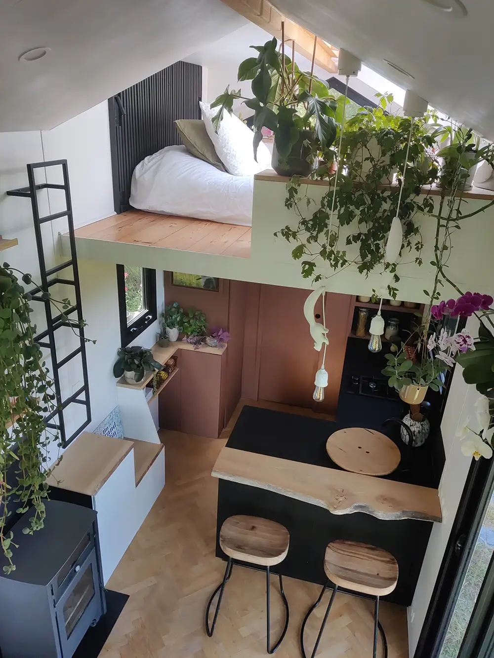 Aménagement intérieur d'une tiny house. Vue de haut de l'espace cuisine et poêle à bois.