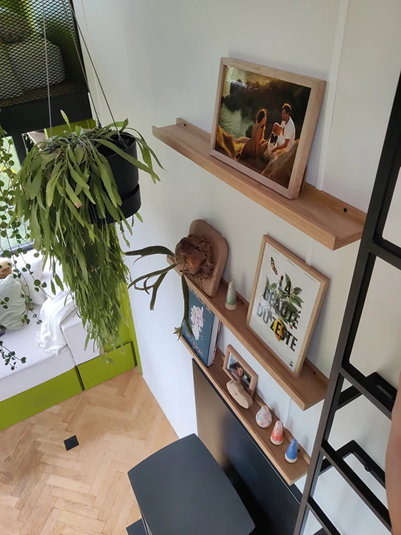 Aménagement intérieur d'une tiny house. Vue de haut des étagères bois chêne au-dessus du poêle à bois.