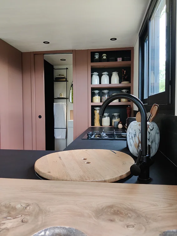 Aménagement intérieur d'une tiny house. Evier de cuisine avec plateau en bois pour gagner de l'espace.