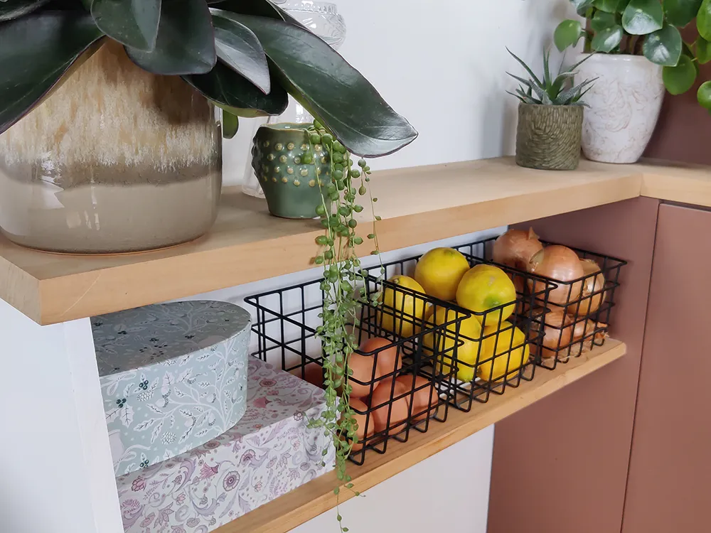 Aménagement intérieur d'une tiny house. Paniers de rangement dans cuisine pour fruits et légumes.