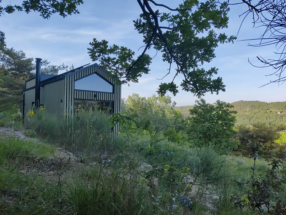 Aménagement intérieur d'une tiny house. Photo extérieure de l'autoconstruction dans la nature.